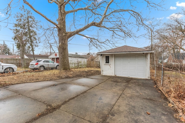 detached garage with concrete driveway and fence