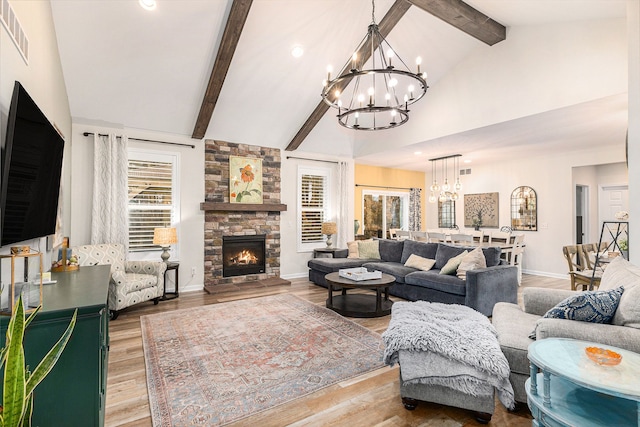 living area featuring a stone fireplace, beamed ceiling, light wood-type flooring, and a notable chandelier