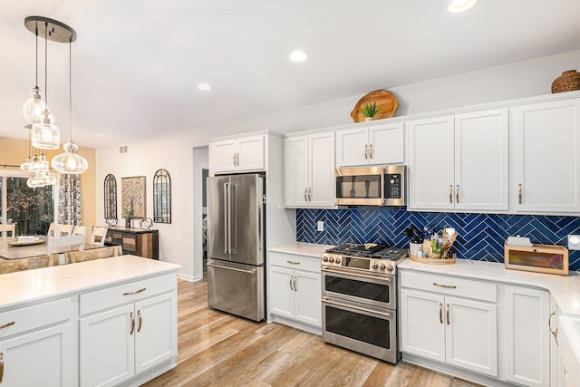 kitchen featuring light wood finished floors, white cabinetry, stainless steel appliances, and light countertops