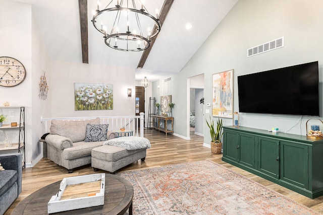 living area featuring high vaulted ceiling, light wood-style flooring, visible vents, and a notable chandelier