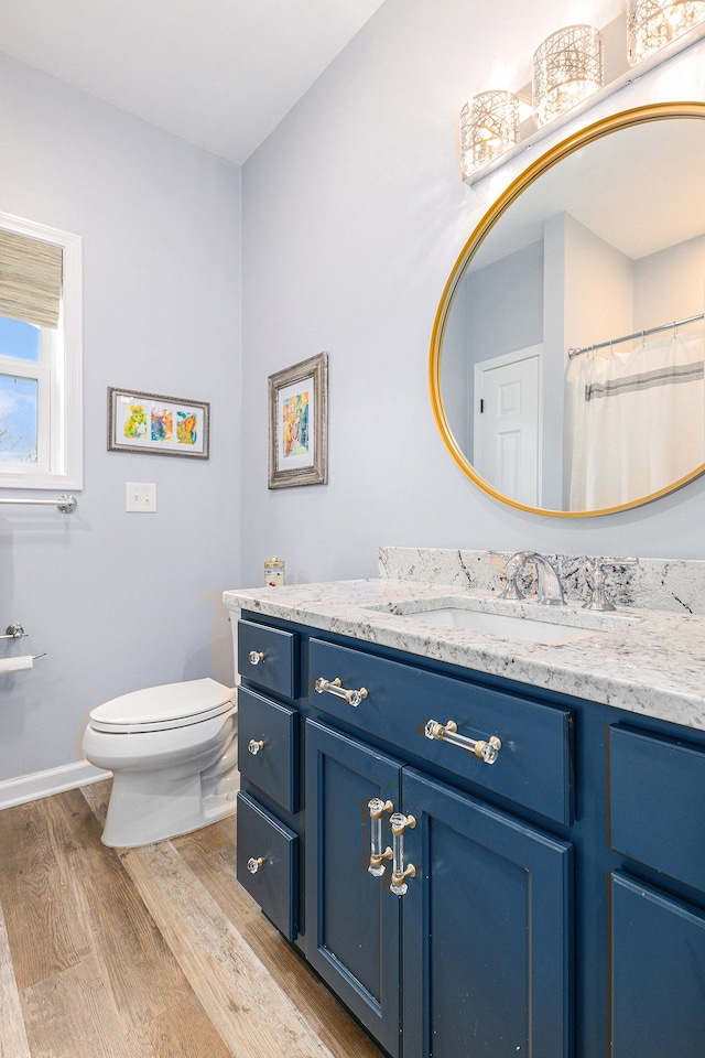 full bath featuring toilet, wood finished floors, vanity, and baseboards