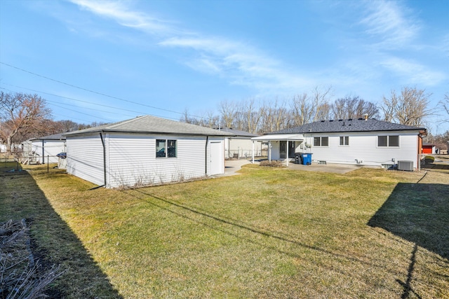 rear view of house with a patio area, central air condition unit, an outbuilding, and a yard