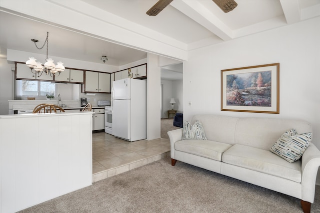 living area with beam ceiling, light carpet, a chandelier, and light tile patterned flooring