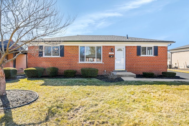 view of front of house featuring brick siding, central AC, a shingled roof, and a front lawn