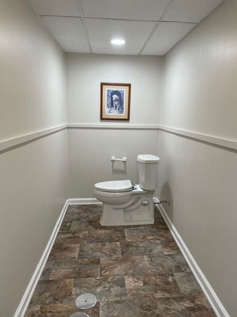 bathroom featuring a drop ceiling, baseboards, and toilet