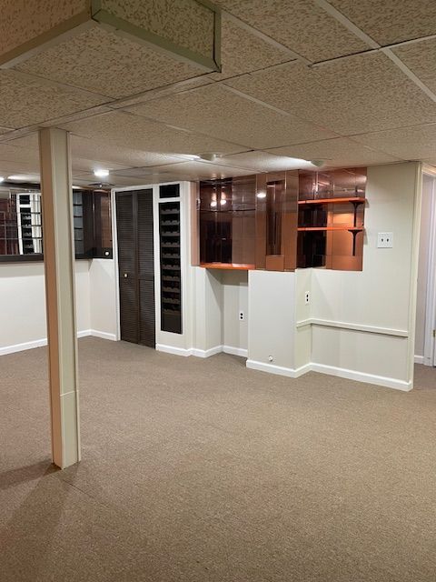 unfurnished room with carpet flooring, a paneled ceiling, and baseboards