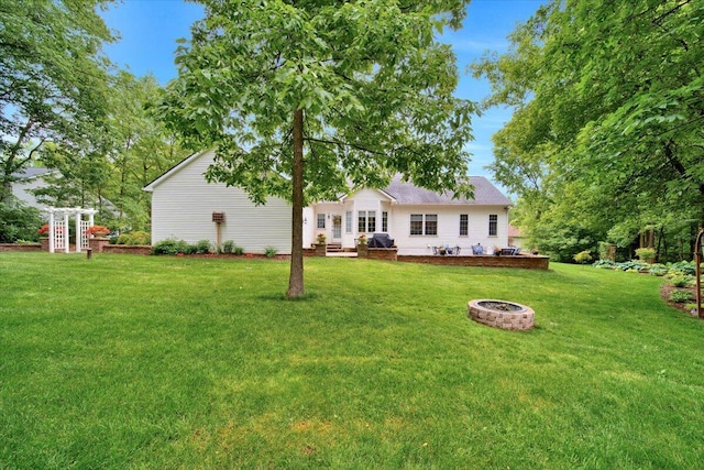 back of property featuring an outdoor fire pit and a yard