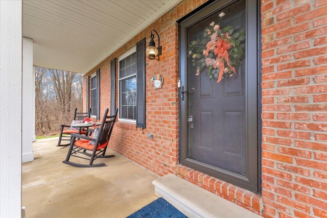 property entrance with a porch and brick siding