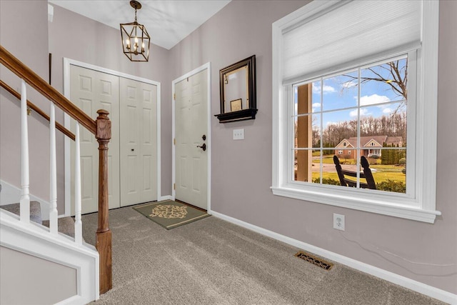 foyer entrance with a chandelier, visible vents, baseboards, stairs, and carpet