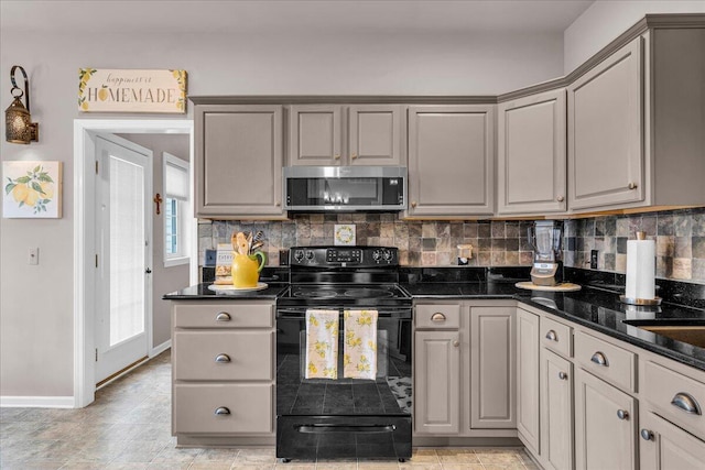 kitchen featuring black electric range, stainless steel microwave, gray cabinets, and backsplash