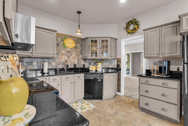 kitchen with a sink, hanging light fixtures, black appliances, tasteful backsplash, and glass insert cabinets