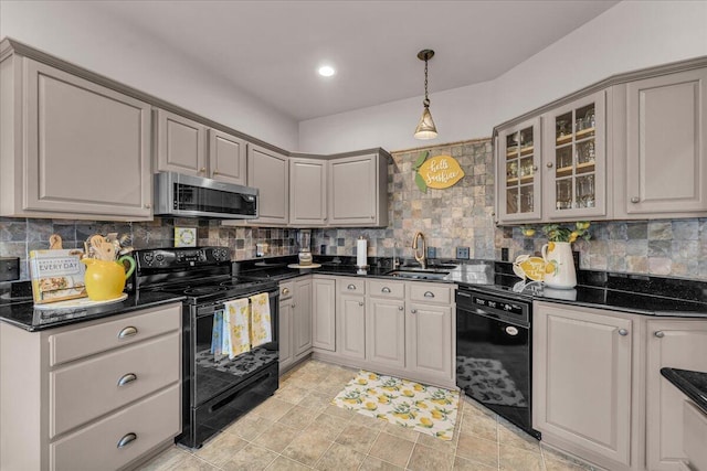 kitchen featuring gray cabinetry, a sink, decorative backsplash, black appliances, and glass insert cabinets