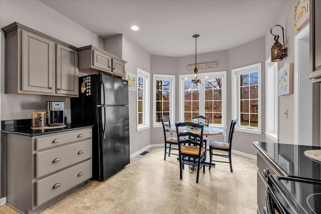 kitchen featuring plenty of natural light, baseboards, dark countertops, freestanding refrigerator, and gray cabinetry