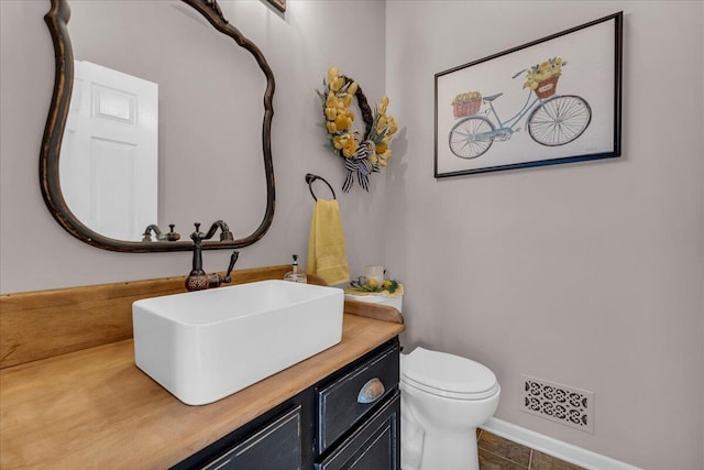 half bathroom with vanity, toilet, and tile patterned floors