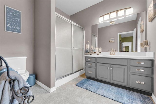 bathroom with a stall shower, baseboards, vanity, and toilet