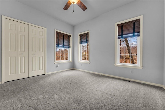 unfurnished bedroom with a ceiling fan, visible vents, baseboards, a closet, and carpet