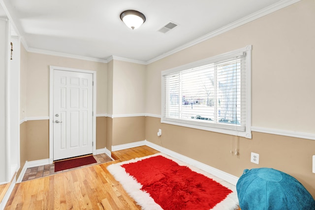 interior space featuring ornamental molding, wood finished floors, visible vents, and baseboards