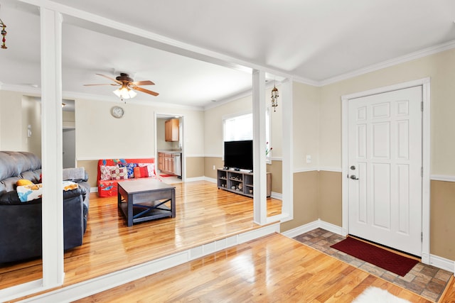 living room featuring ornamental molding, baseboards, and wood finished floors