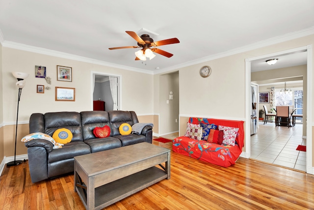 living room featuring a ceiling fan, baseboards, ornamental molding, and wood finished floors