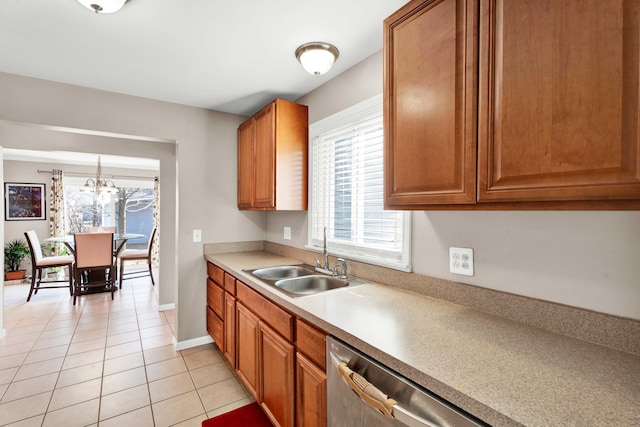 kitchen featuring light tile patterned floors, light countertops, brown cabinetry, a sink, and dishwasher