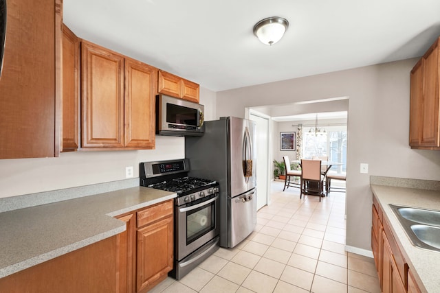 kitchen with light tile patterned floors, light countertops, appliances with stainless steel finishes, and a sink