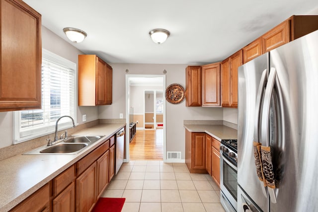 kitchen featuring light tile patterned floors, visible vents, appliances with stainless steel finishes, light countertops, and a sink