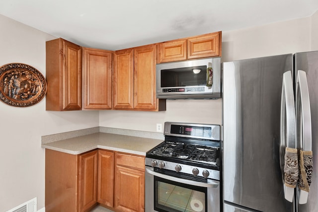 kitchen with brown cabinets, visible vents, appliances with stainless steel finishes, and light countertops