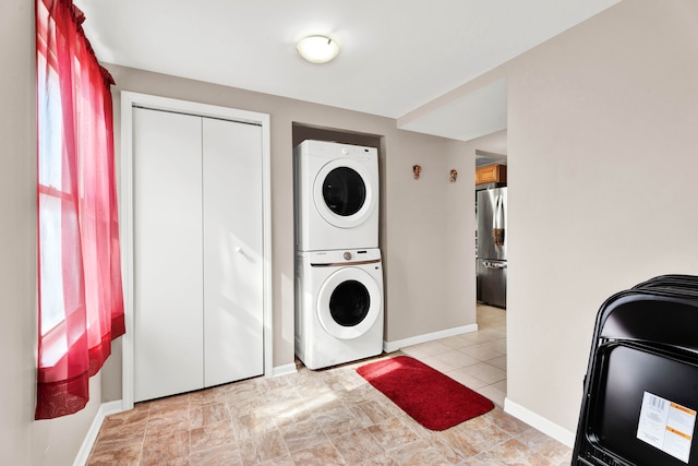 clothes washing area featuring stacked washer and dryer, baseboards, and laundry area