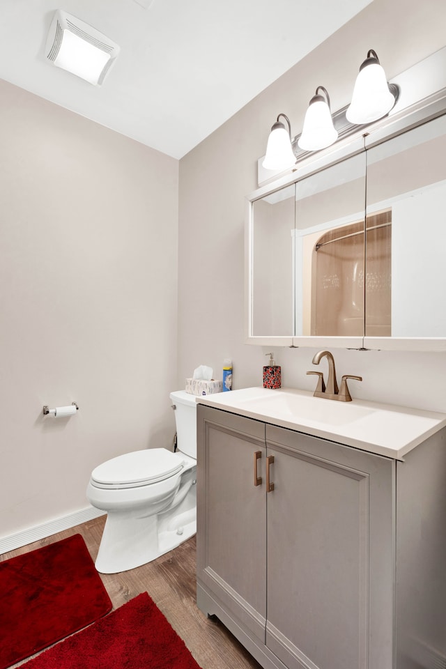 bathroom with toilet, wood finished floors, visible vents, vanity, and baseboards