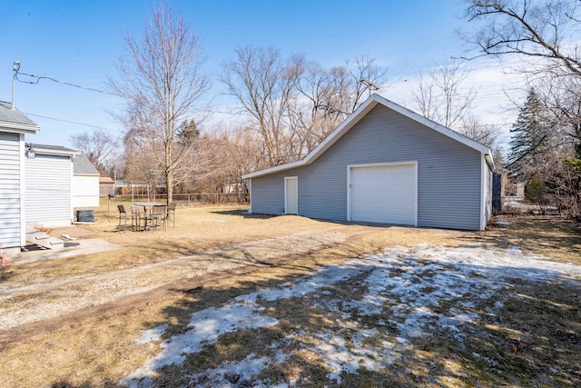 detached garage featuring driveway and fence