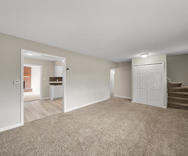 interior space featuring light carpet, baseboards, and stairs