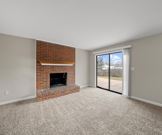 unfurnished living room with carpet floors, a brick fireplace, and baseboards