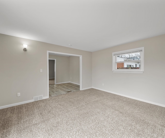 spare room with light colored carpet, visible vents, and baseboards