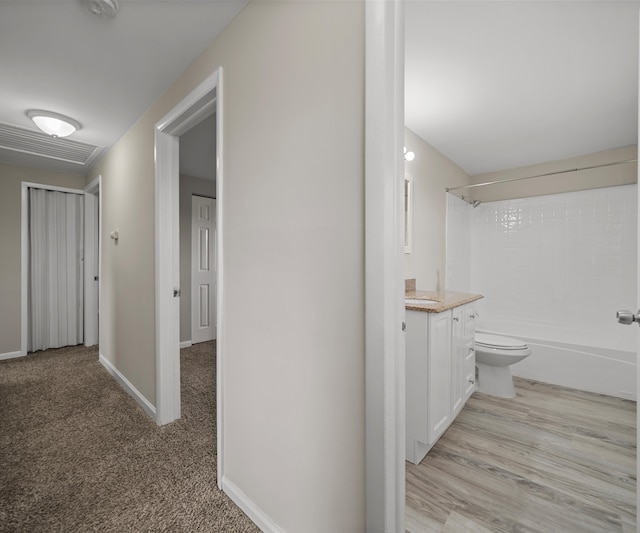 hallway featuring baseboards, visible vents, and light colored carpet