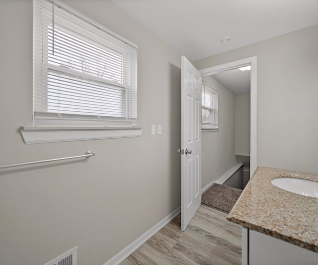 bathroom with plenty of natural light, wood finished floors, vanity, and baseboards