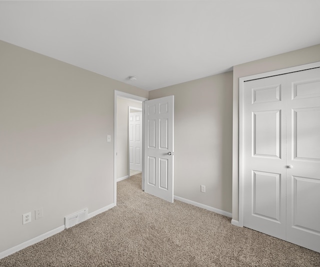 unfurnished bedroom featuring a closet, light colored carpet, and baseboards