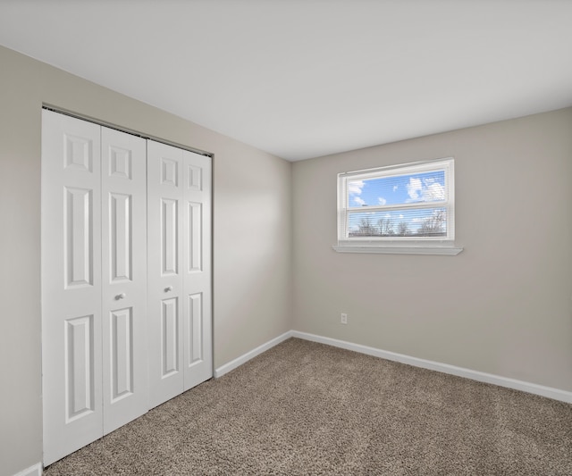 unfurnished bedroom with carpet floors, a closet, and baseboards