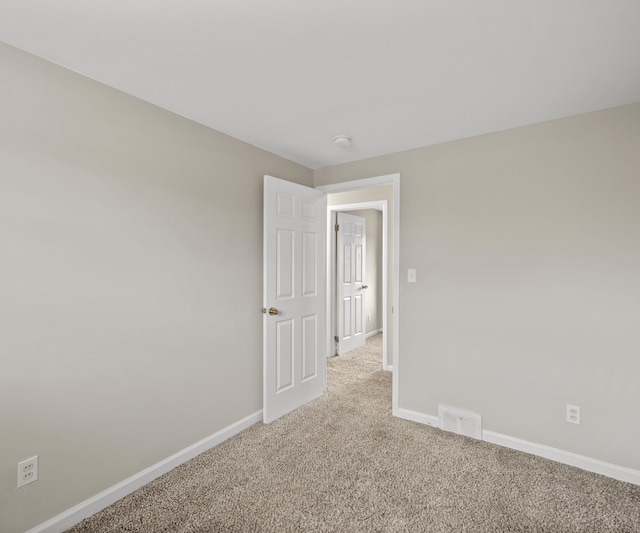 carpeted spare room with visible vents and baseboards