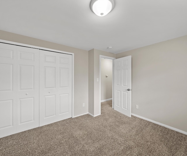 unfurnished bedroom featuring carpet floors, baseboards, and a closet