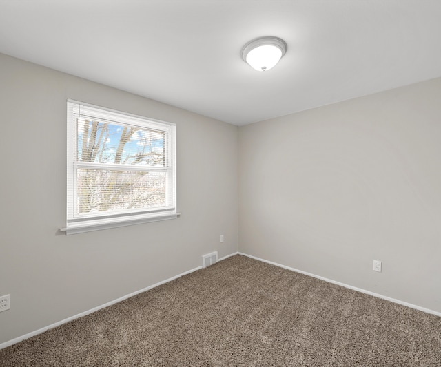 carpeted spare room featuring visible vents and baseboards