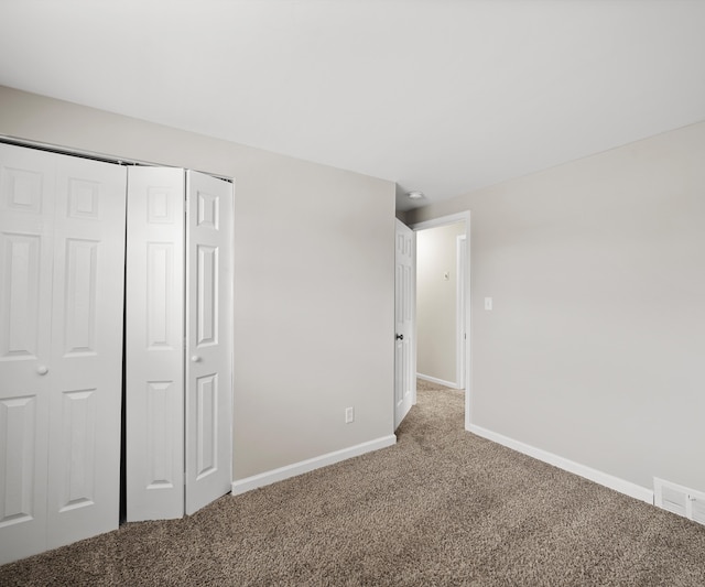 unfurnished bedroom with carpet, a closet, visible vents, and baseboards