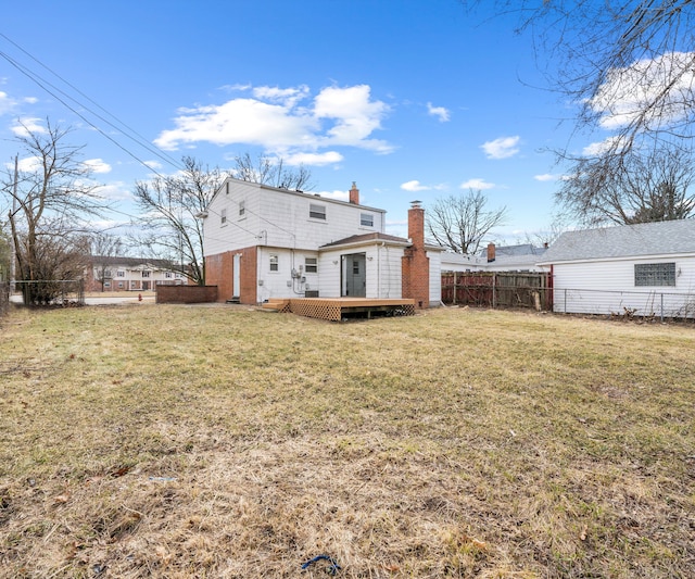 back of house with a lawn, a chimney, fence, and a wooden deck