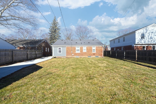 rear view of house with a yard, a fenced backyard, and brick siding