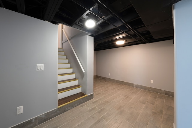 finished below grade area with stairway, wood finished floors, and baseboards