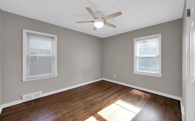 empty room with a ceiling fan, dark wood-style floors, visible vents, and baseboards