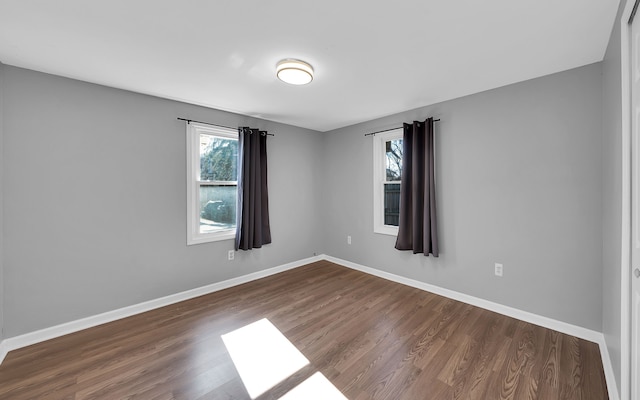 empty room with dark wood-type flooring and baseboards