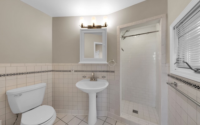 full bathroom featuring toilet, tile walls, wainscoting, and a shower stall