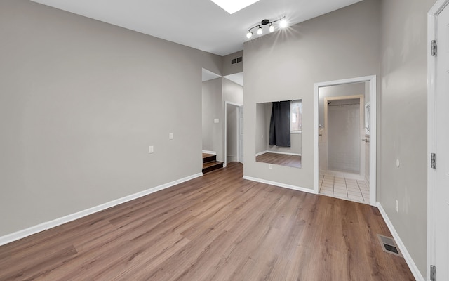 unfurnished living room with visible vents, light wood-style flooring, and baseboards