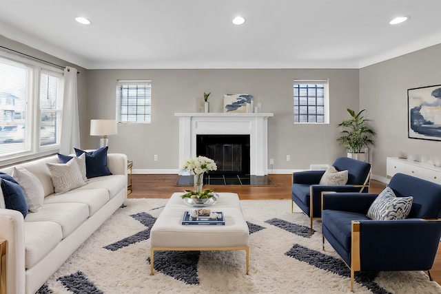 living room featuring a fireplace with flush hearth, a healthy amount of sunlight, and wood finished floors