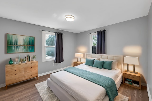 bedroom featuring multiple windows, wood finished floors, and baseboards